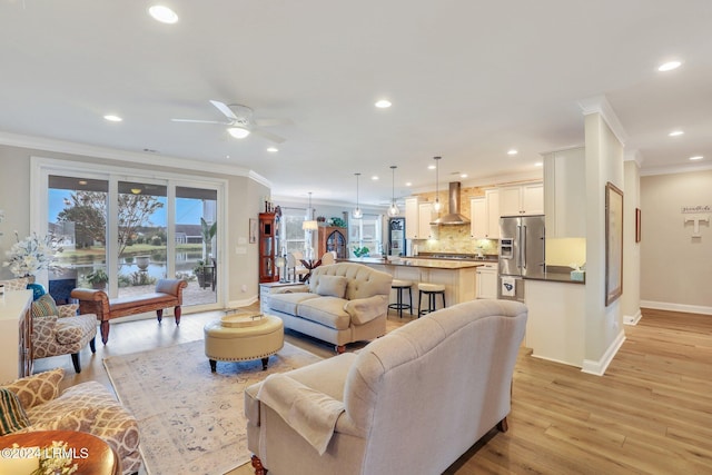 living room with ornamental molding, light hardwood / wood-style floors, and ceiling fan