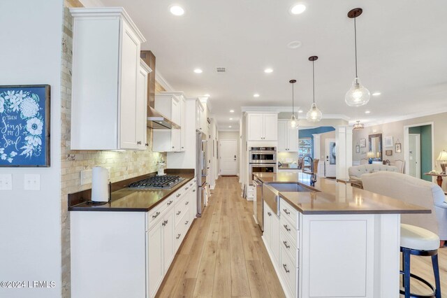 kitchen featuring pendant lighting, sink, appliances with stainless steel finishes, white cabinetry, and backsplash