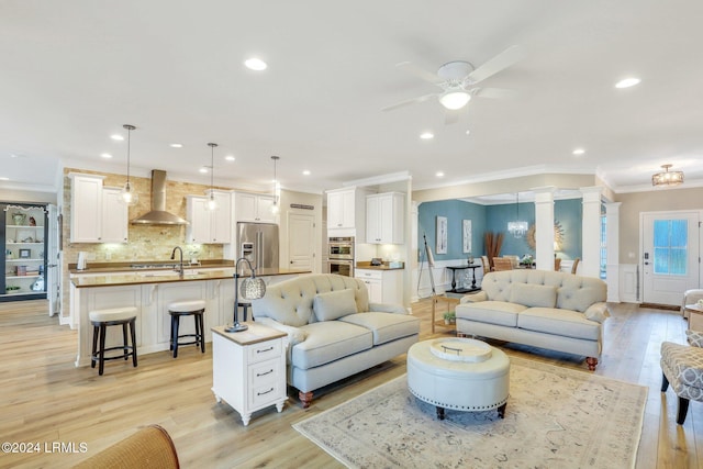 living room with crown molding, ceiling fan, sink, and light wood-type flooring