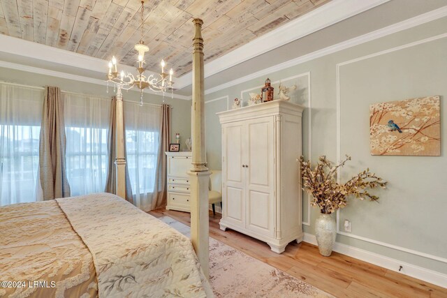 bedroom with an inviting chandelier, multiple windows, ornamental molding, and light hardwood / wood-style flooring