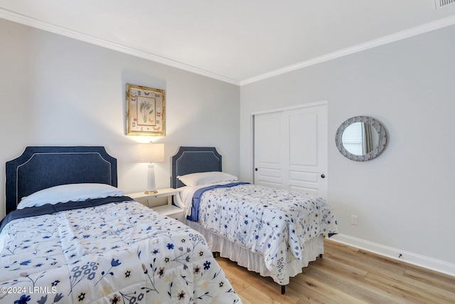 bedroom featuring crown molding, light hardwood / wood-style flooring, and a closet