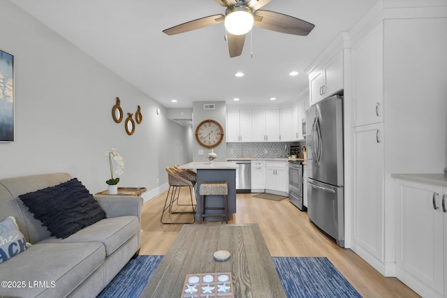 living room with ceiling fan and light wood-type flooring