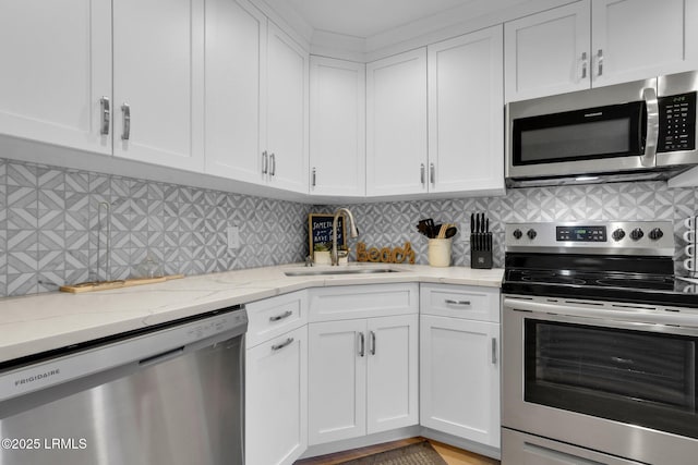 kitchen with appliances with stainless steel finishes, light stone countertops, sink, and white cabinets