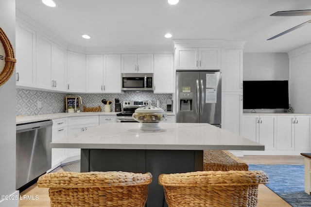 kitchen featuring stainless steel appliances, white cabinetry, a kitchen island, and backsplash