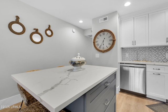 kitchen featuring stainless steel dishwasher, white cabinets, a kitchen bar, and decorative backsplash