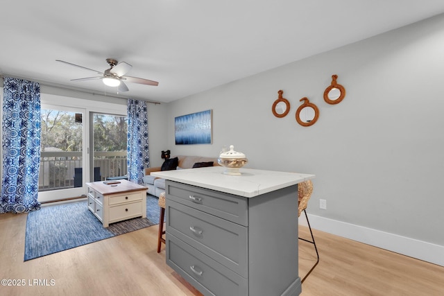 kitchen featuring a center island, light hardwood / wood-style floors, a breakfast bar area, and gray cabinetry