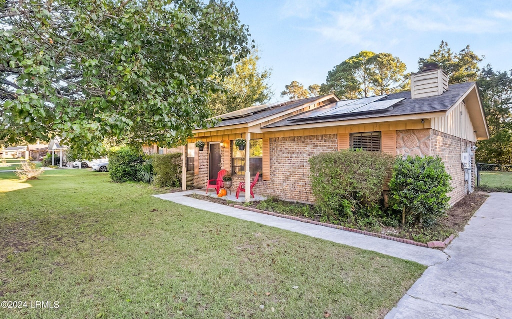 ranch-style house featuring a front yard and solar panels