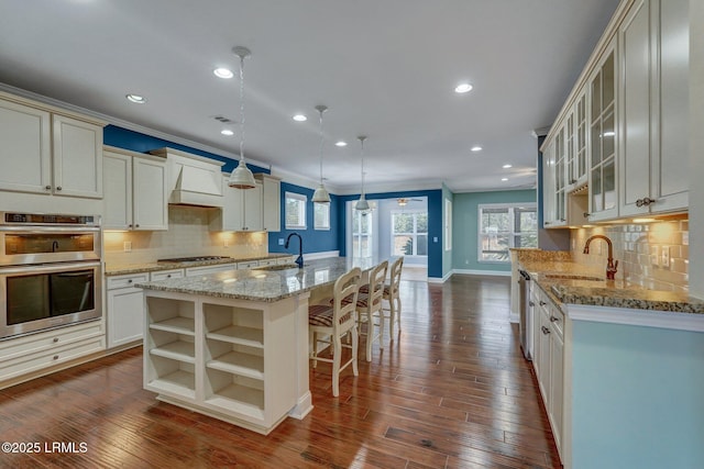 kitchen featuring hanging light fixtures, stainless steel appliances, sink, and a center island with sink