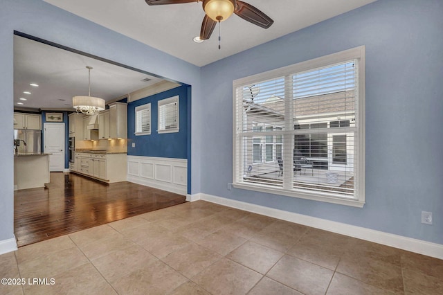 unfurnished room featuring ceiling fan with notable chandelier and light tile patterned floors