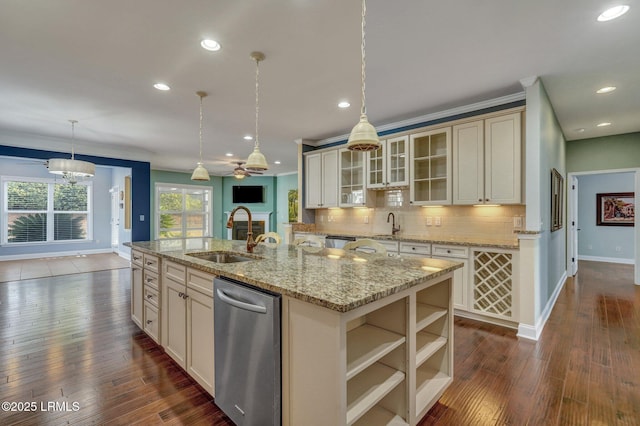 kitchen featuring sink, tasteful backsplash, decorative light fixtures, a center island with sink, and cream cabinets