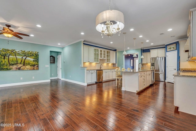 kitchen featuring appliances with stainless steel finishes, decorative light fixtures, sink, a kitchen bar, and a kitchen island with sink