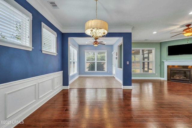 unfurnished dining area with hardwood / wood-style floors, ornamental molding, and ceiling fan