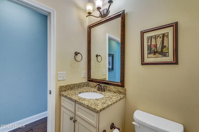 bathroom featuring hardwood / wood-style flooring, vanity, toilet, and an inviting chandelier