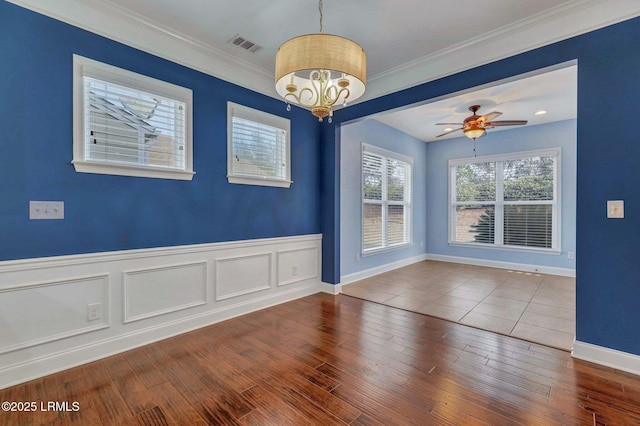 empty room with crown molding, ceiling fan with notable chandelier, and hardwood / wood-style floors