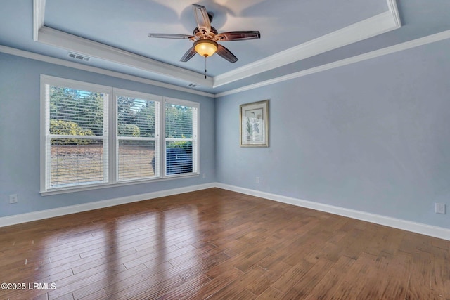 unfurnished room featuring a raised ceiling, ornamental molding, and dark hardwood / wood-style flooring