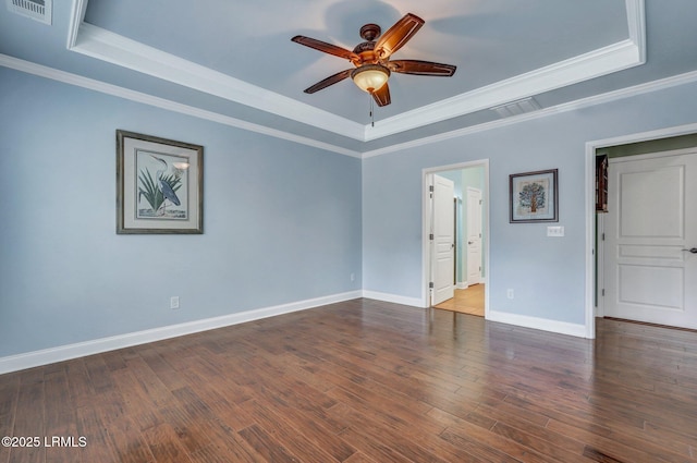 empty room featuring dark hardwood / wood-style floors, ornamental molding, a raised ceiling, and ceiling fan