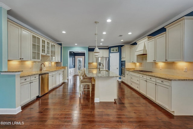 kitchen with appliances with stainless steel finishes, a kitchen island with sink, dark hardwood / wood-style flooring, decorative light fixtures, and custom exhaust hood