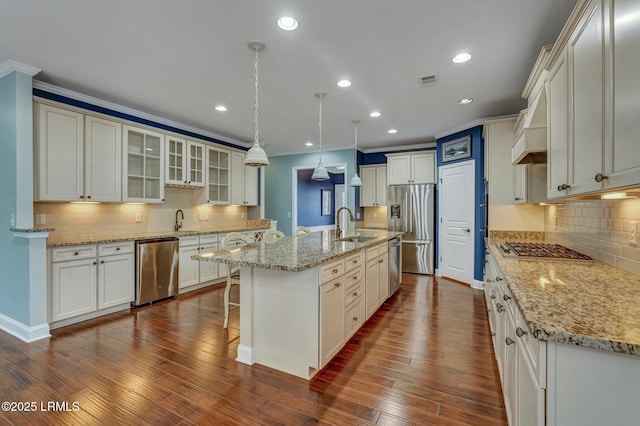 kitchen with a large island, dark wood-type flooring, appliances with stainless steel finishes, hanging light fixtures, and a kitchen breakfast bar