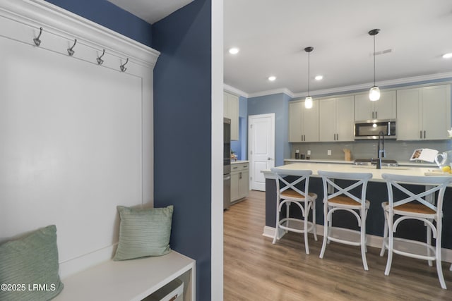 587 Hulston Landing Rd, Bluffton, SC 29909 - kitchen featuring stainless steel microwave, light countertops, a breakfast bar area, wood finished floors, and tasteful backsplash