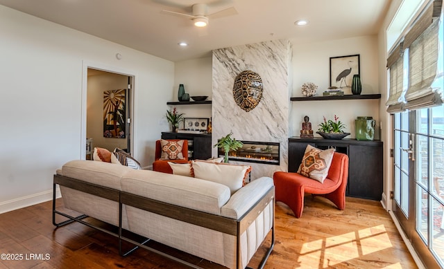 living room with baseboards, recessed lighting, a fireplace, a ceiling fan, and wood-type flooring