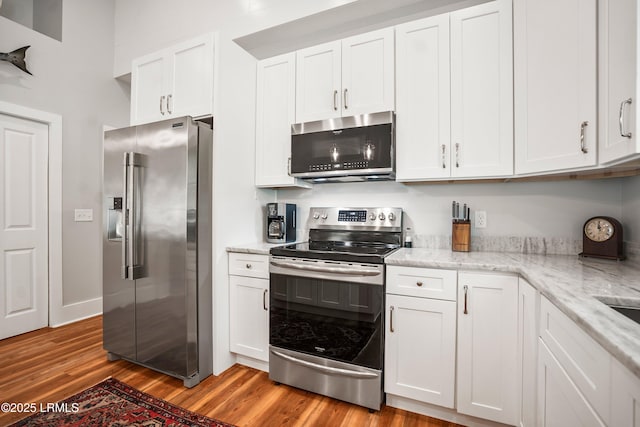 1 William St, Beaufort, SC 29907 - kitchen featuring light wood finished floors, stainless steel appliances, light stone counters, and white cabinets