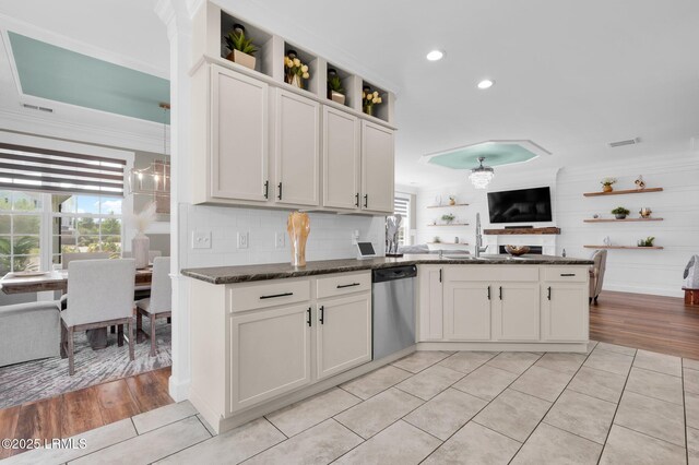 kitchen featuring a sink, dishwasher, a peninsula, light tile patterned floors, and ornamental molding