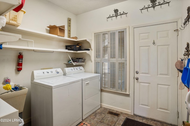 laundry area featuring washing machine and clothes dryer and a textured ceiling