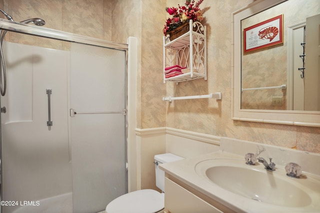 bathroom featuring vanity, a shower with door, and toilet