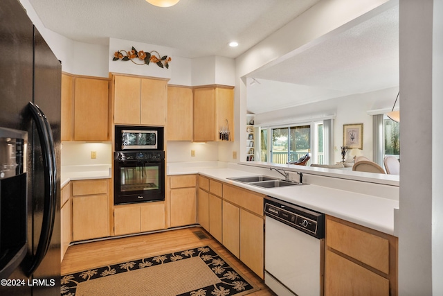 kitchen featuring light brown cabinetry, black appliances, sink, kitchen peninsula, and light hardwood / wood-style flooring