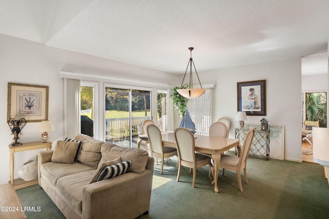 dining space featuring a textured ceiling and dark colored carpet