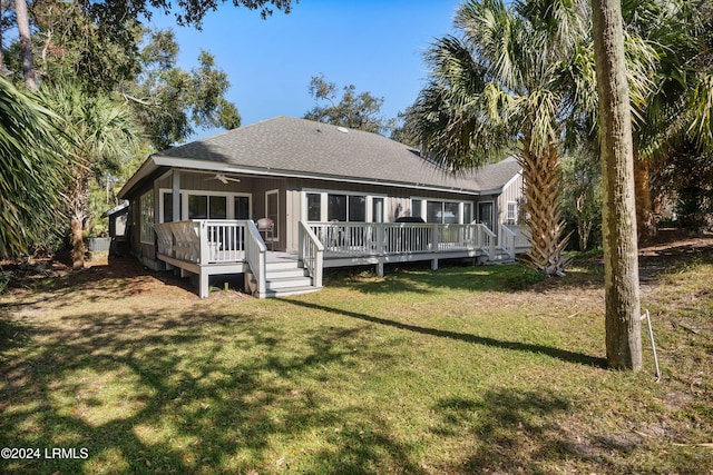 rear view of house featuring ceiling fan, a sunroom, a deck, and a lawn