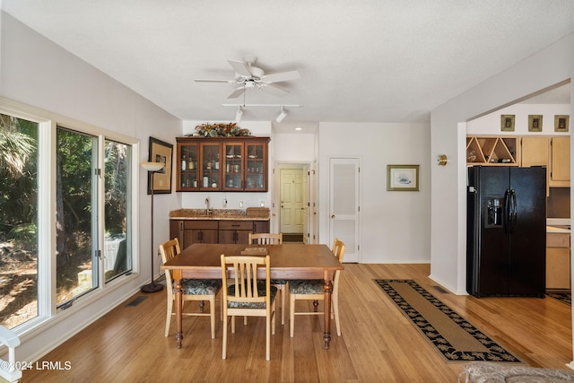 dining area featuring ceiling fan, indoor wet bar, and light hardwood / wood-style floors