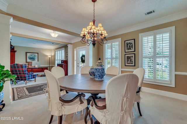 carpeted dining area featuring decorative columns, ornamental molding, an inviting chandelier, and a textured ceiling