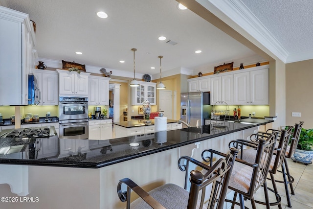 kitchen featuring crown molding, hanging light fixtures, kitchen peninsula, stainless steel appliances, and white cabinets