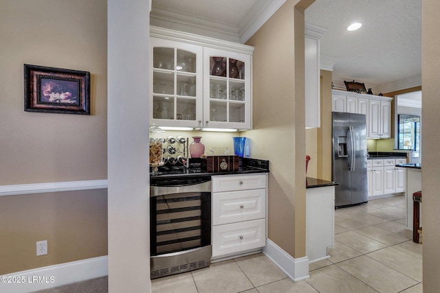 bar featuring white cabinetry, crown molding, light tile patterned floors, stainless steel fridge, and beverage cooler