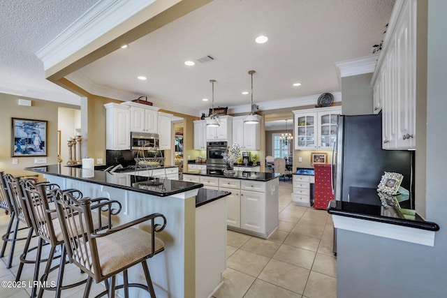 kitchen featuring light tile patterned flooring, appliances with stainless steel finishes, pendant lighting, white cabinetry, and kitchen peninsula