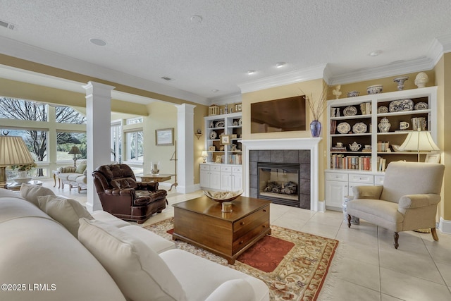 living room with ornamental molding, a tiled fireplace, decorative columns, and light tile patterned floors