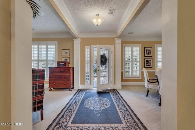 carpeted entryway featuring crown molding, decorative columns, and a textured ceiling