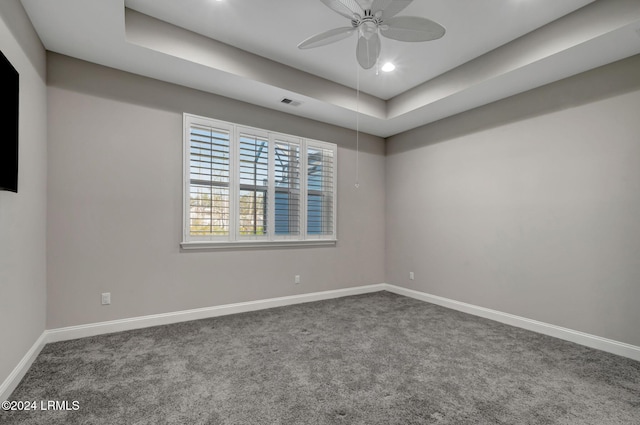 spare room featuring carpet, ceiling fan, and a tray ceiling