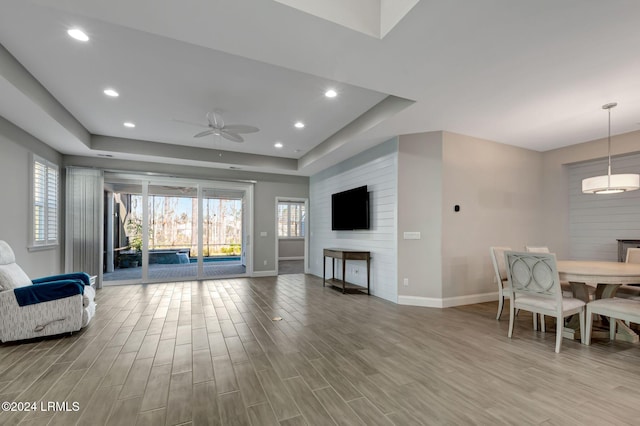 living room with a raised ceiling and ceiling fan