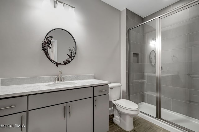 bathroom featuring vanity, a shower with shower door, and toilet