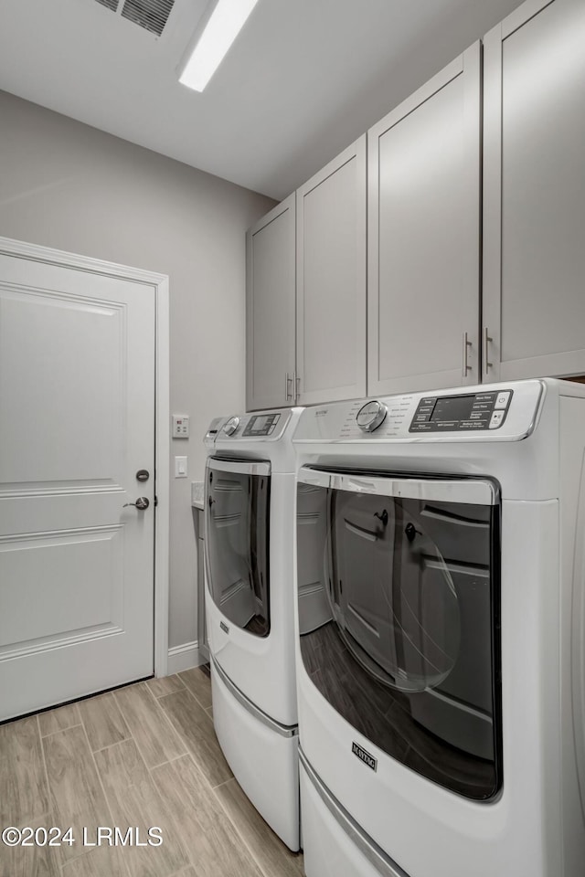 clothes washing area featuring cabinets and washer and dryer