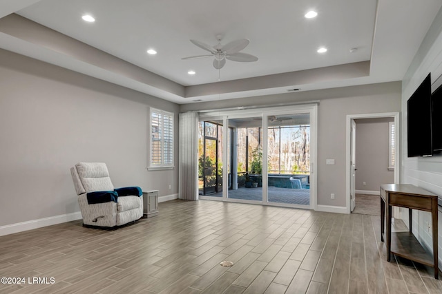 sitting room with a raised ceiling and ceiling fan