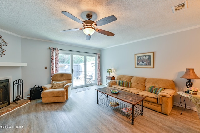 living room with crown molding, ceiling fan, light hardwood / wood-style floors, and a textured ceiling