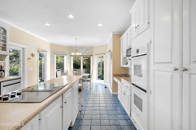 kitchen featuring white cabinetry, crown molding, decorative light fixtures, black electric cooktop, and dishwasher