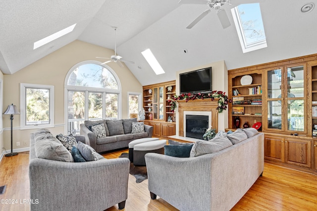 living room with built in features, ceiling fan, and light hardwood / wood-style flooring