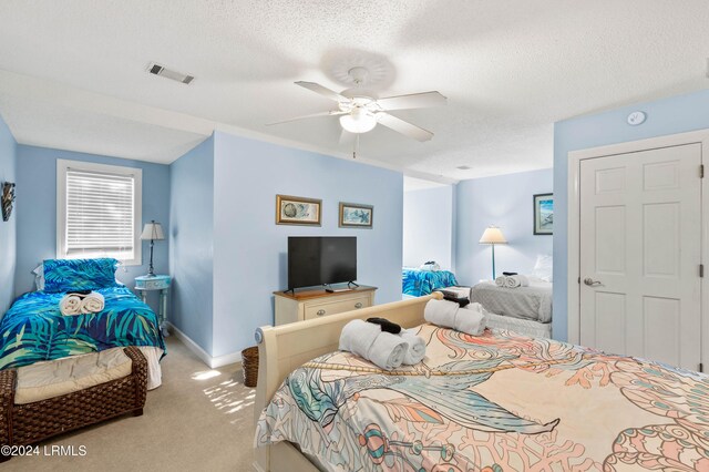 bedroom featuring light carpet, ceiling fan, and a textured ceiling