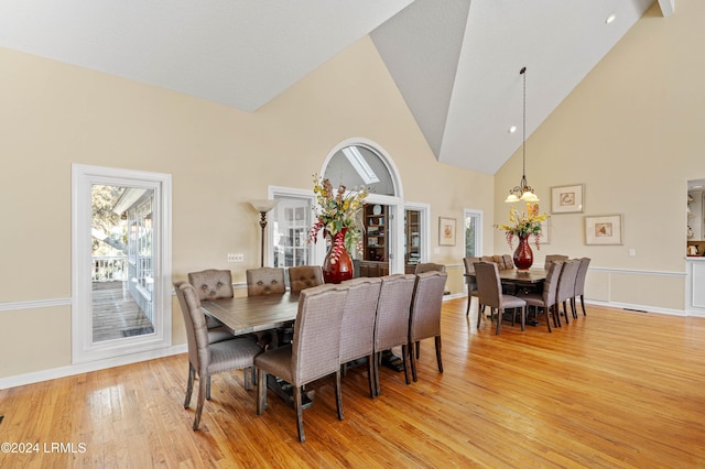 dining room with an inviting chandelier, light hardwood / wood-style flooring, high vaulted ceiling, and a healthy amount of sunlight