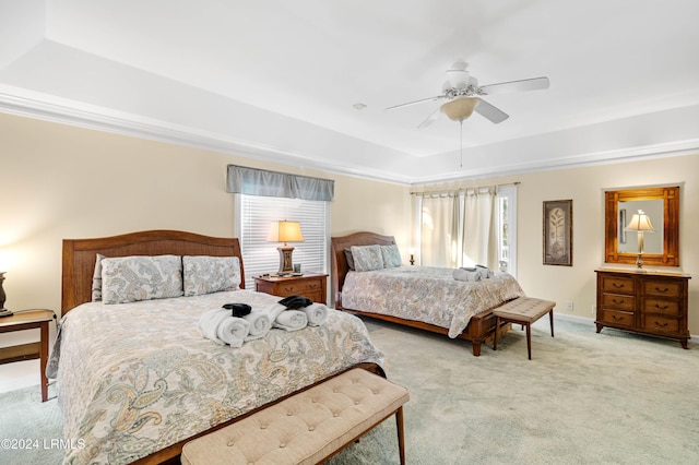 carpeted bedroom with a tray ceiling and ceiling fan