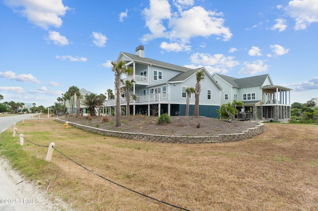rear view of house with a balcony and a lawn